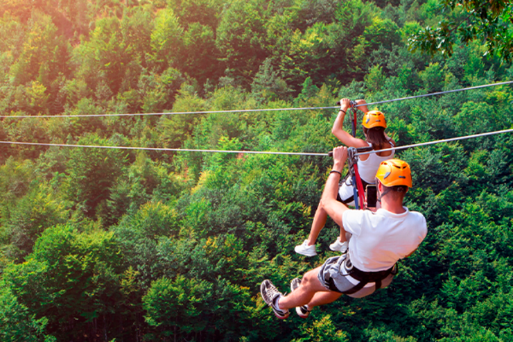 cenário de um casal suspenso nos cabos de uma tirolesa em meio a natureza