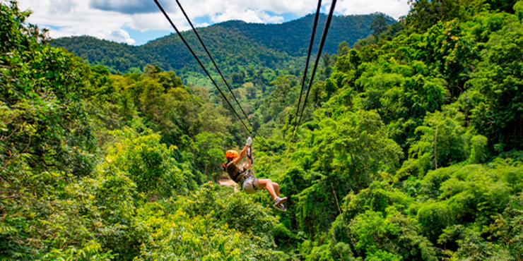 cenário de uma mulher suspensa pelos cabos de uma tirolesa em meio às montanhas de Monte Verde