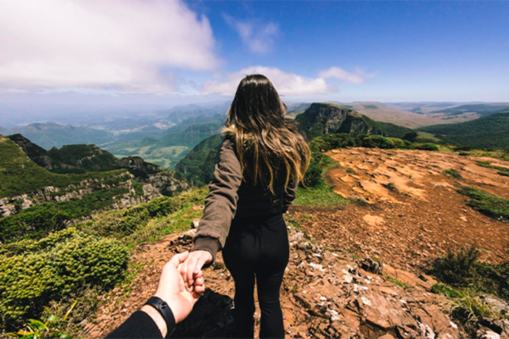 Turistas de mão dada contemplando natureza de lugares para viajar no frio