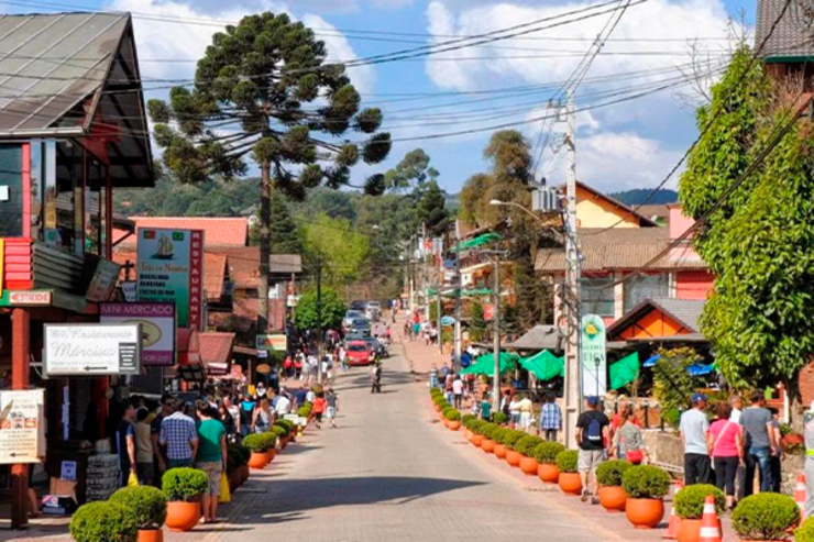 cenário da rua principal de Monte Verde com turistas passeando pelos comércios locais